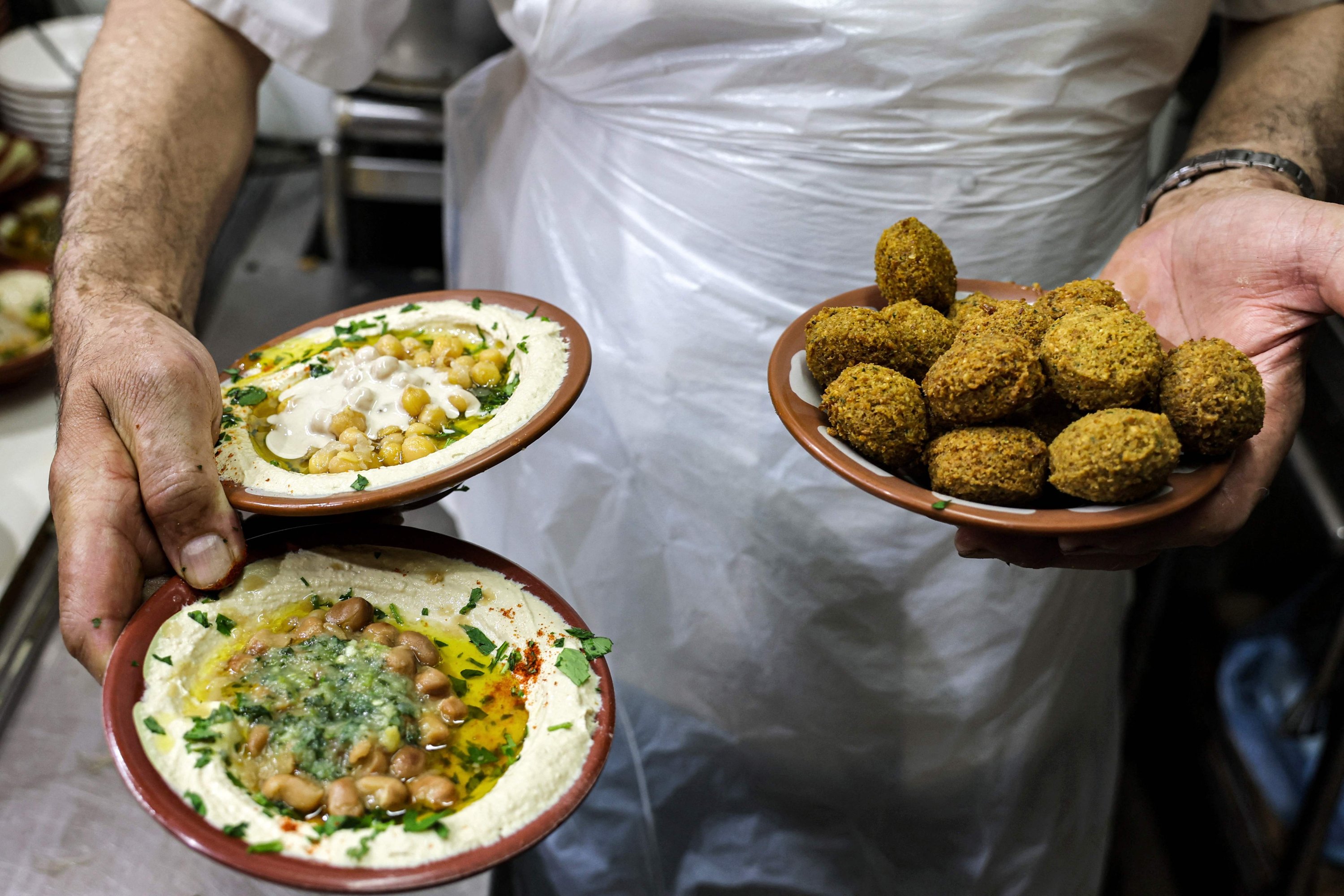 Un cuisinier montre des plats de hommos et de falafel dans un restaurant de Jérusalem-Est, en Cisjordanie occupée, le 26 juillet 2022. Photo AFP