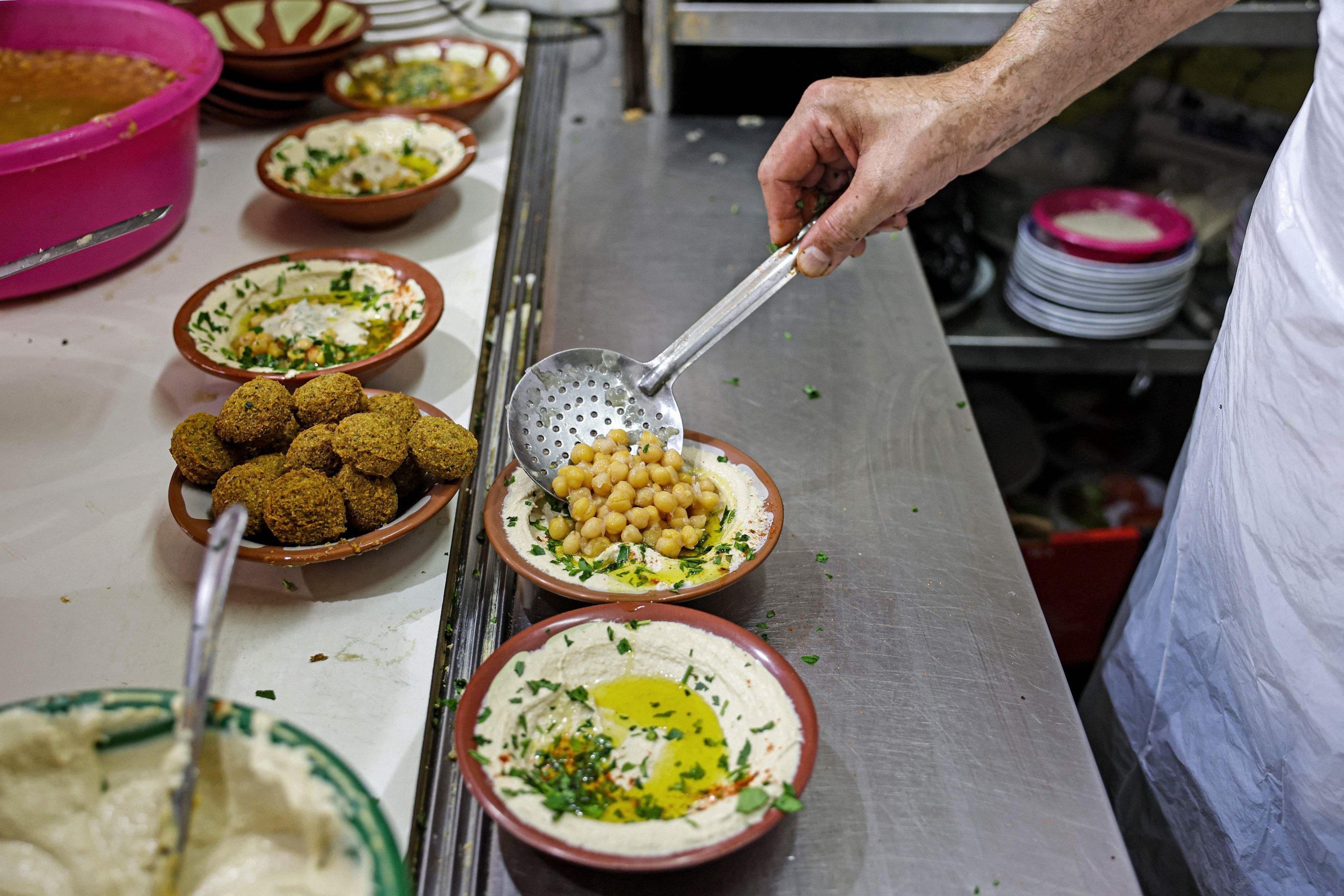 Un cuisinier montre des plats de hommos et de falafel dans un restaurant de Jérusalem-Est, en Cisjordanie occupée, le 26 juillet 2022. Photo AFP