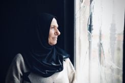 Rosa Srour regardant par une fenêtre de sa maison endommagée par une frappe aérienne israélienne à Aita al-Shaab, dans le sud du Liban, le 27 novembre 2023 (Photo Olivia Le Poidevin / L'Orient-Le Jour)