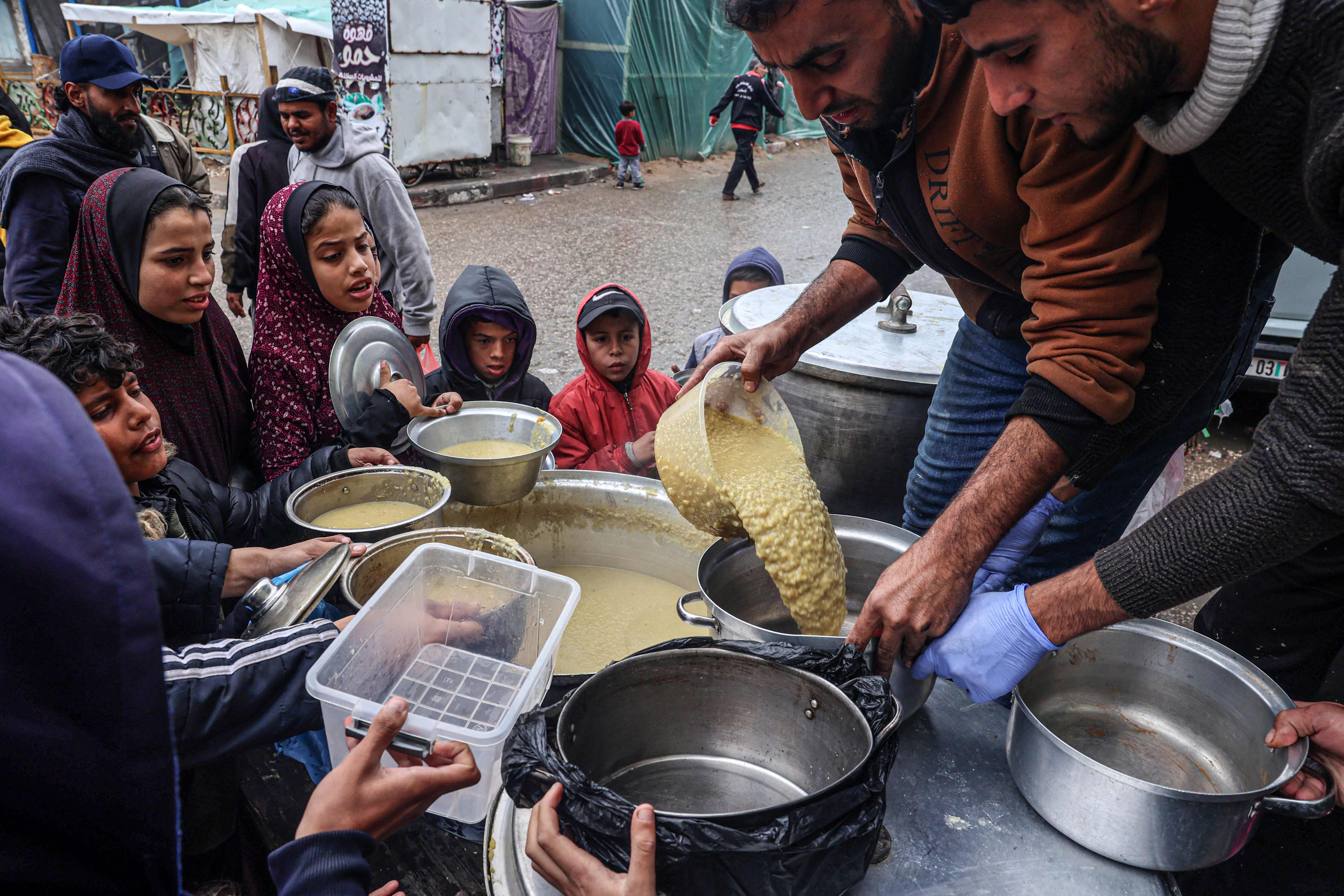 Des volontaires distribuent des rations de soupe de lentille à des Palestiniens déplacés à Rafah, le 18 février 2024 (Photo Said KHATIB / AFP)