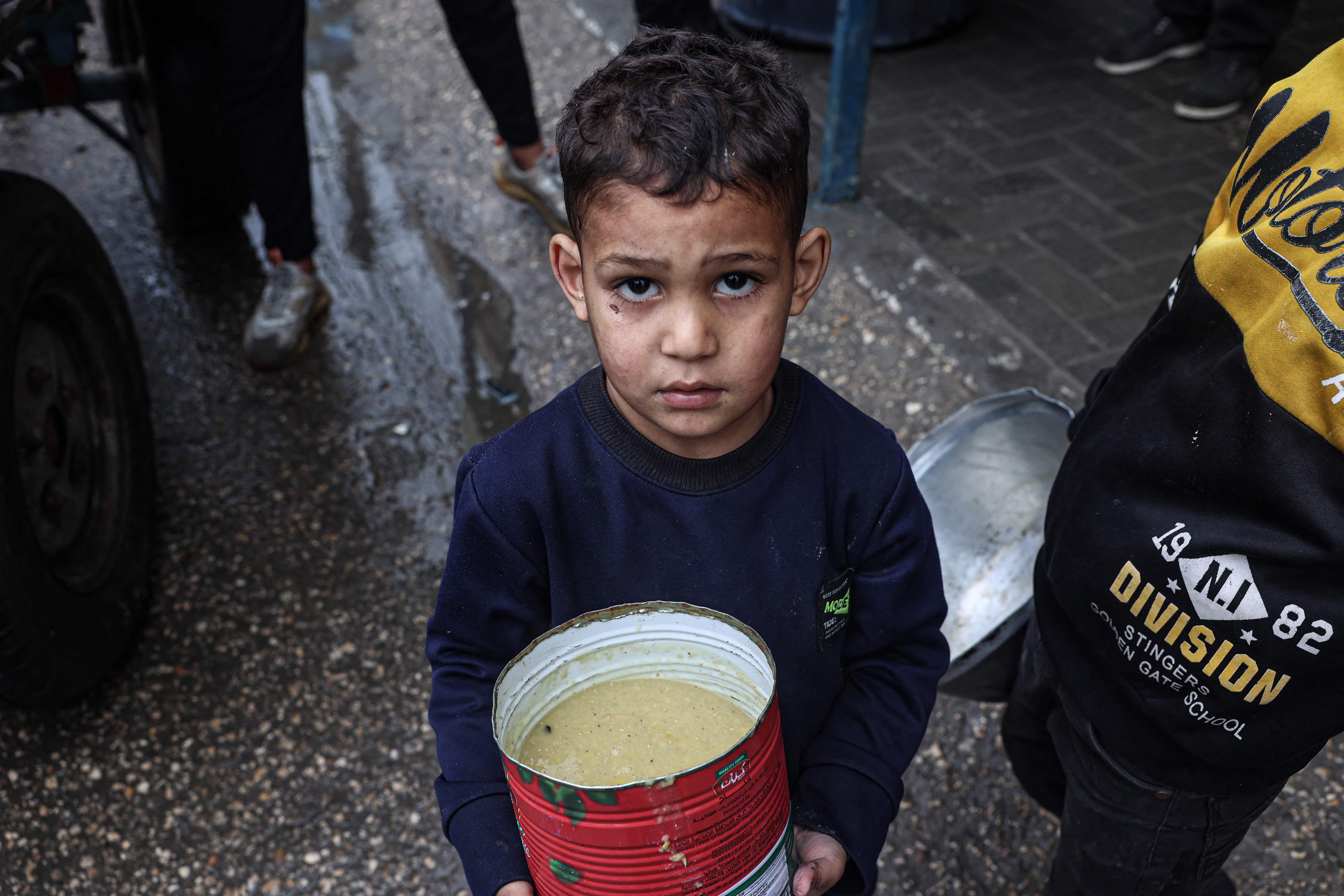 Un garçon palestinien déplacé avec sa ration de soupe de lentille, distribuée par des volontaires dans la ville de Rafah, le 18 février 2024 (Photo Said KHATIB / AFP)