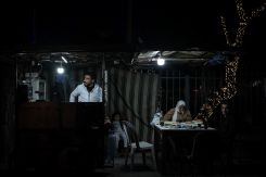 Mona and her husband eat under the light of their falafel stand. (Credit: João Sousa/L'Orient Today)