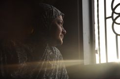 Nawzat stares out the window as she waits for her son to come home. (Credit: Siraj Hasan/L'Orient Today)
