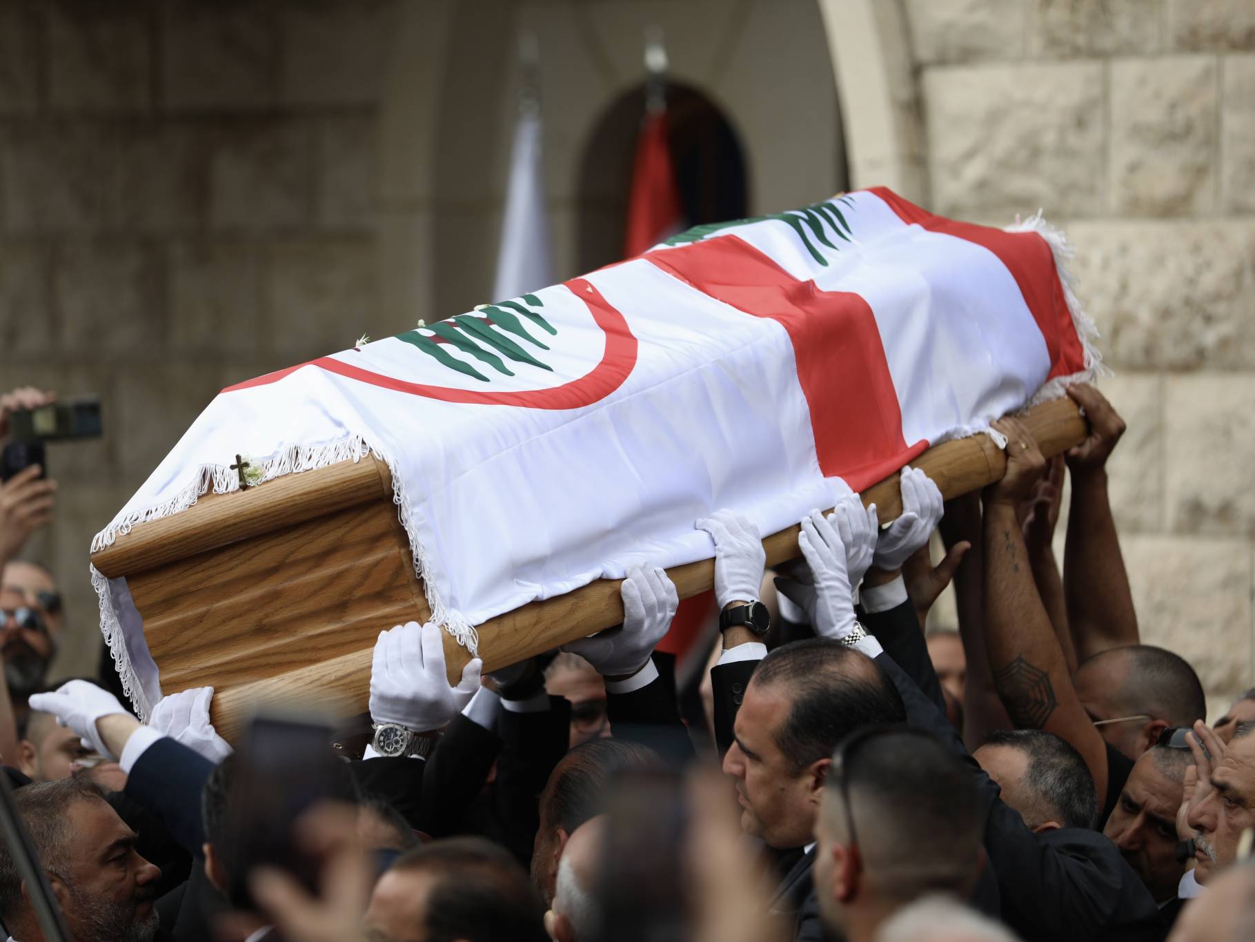 Peu avant 15h, le cercueil de Pascal Sleiman est porté à bout de bras à l'extérieur de l'église pour l'ultime chemin vers Mayfouk, son village natal où il sera enterré. Entre temps, l'enquête des autorités, qui peine à convaincre une large partie des militants FL, se poursuit. La tension dans le pays, elle, reste palpable. Photo Matthieu Karam