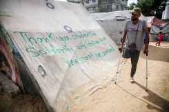 A man uses crutches as he walks past a tent sprayed with a message in solidarity with pro-Palestinian university students, amid the ongoing conflict between Israel and Palestinians, in Rafah in the southern Gaza Strip, April 27, 2024. (Credit: REUTERS/Hatem Khaled)