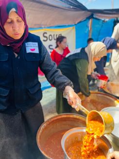 Nivine al-Madhoun, a soup kitchen volunteer and resident of Gaza, serves food at a displacement camp. (Courtesy of: Nivine al-Madhoun)
