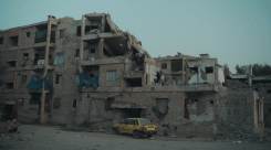 Families live in the rubble of a building partly destroyed by the International Coalition to Fight the Islamic State. (Credit: Bernard Jallet)
