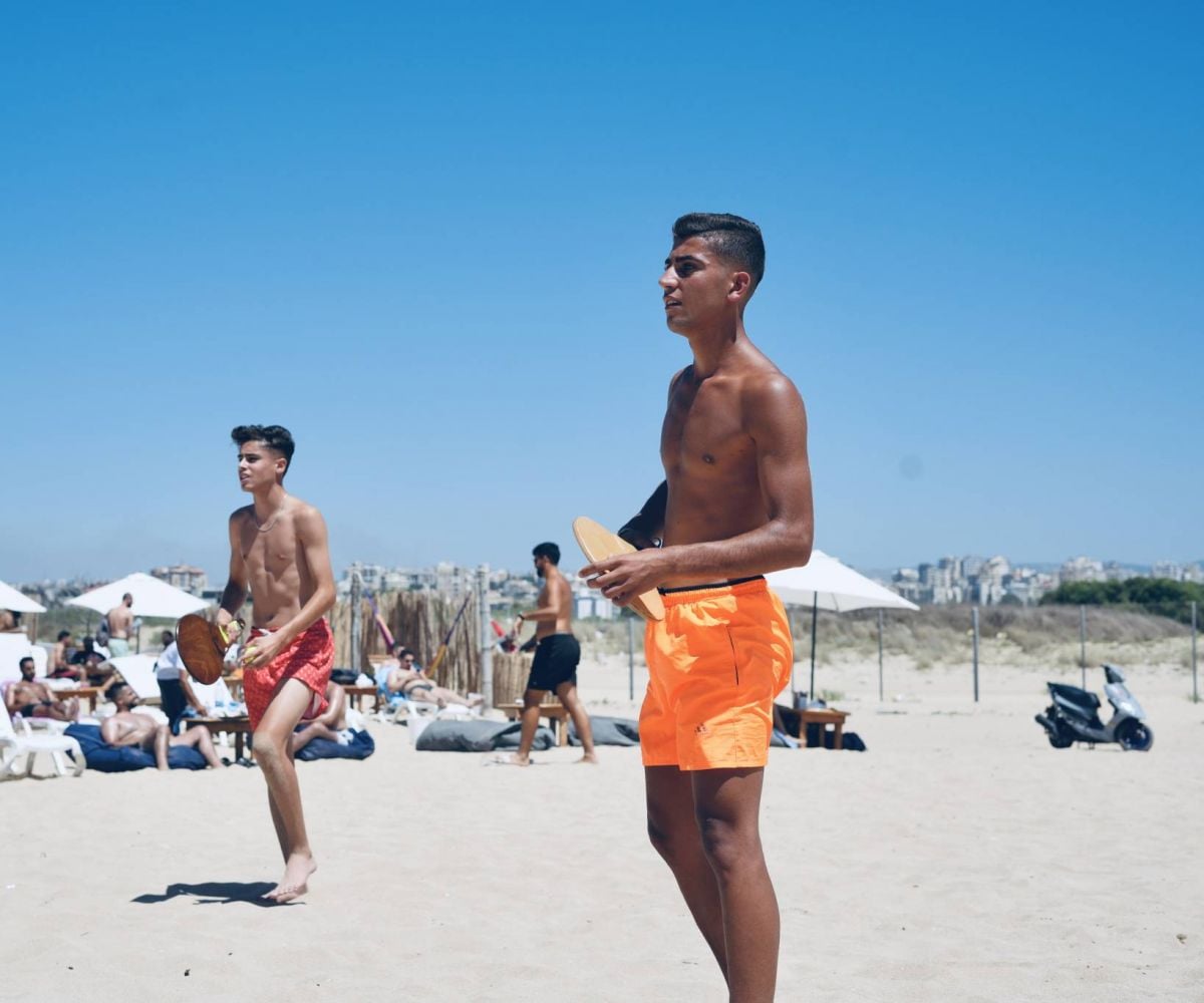 In Sour, beachgoers bathe in the water while Israeli bombs fall in the distance