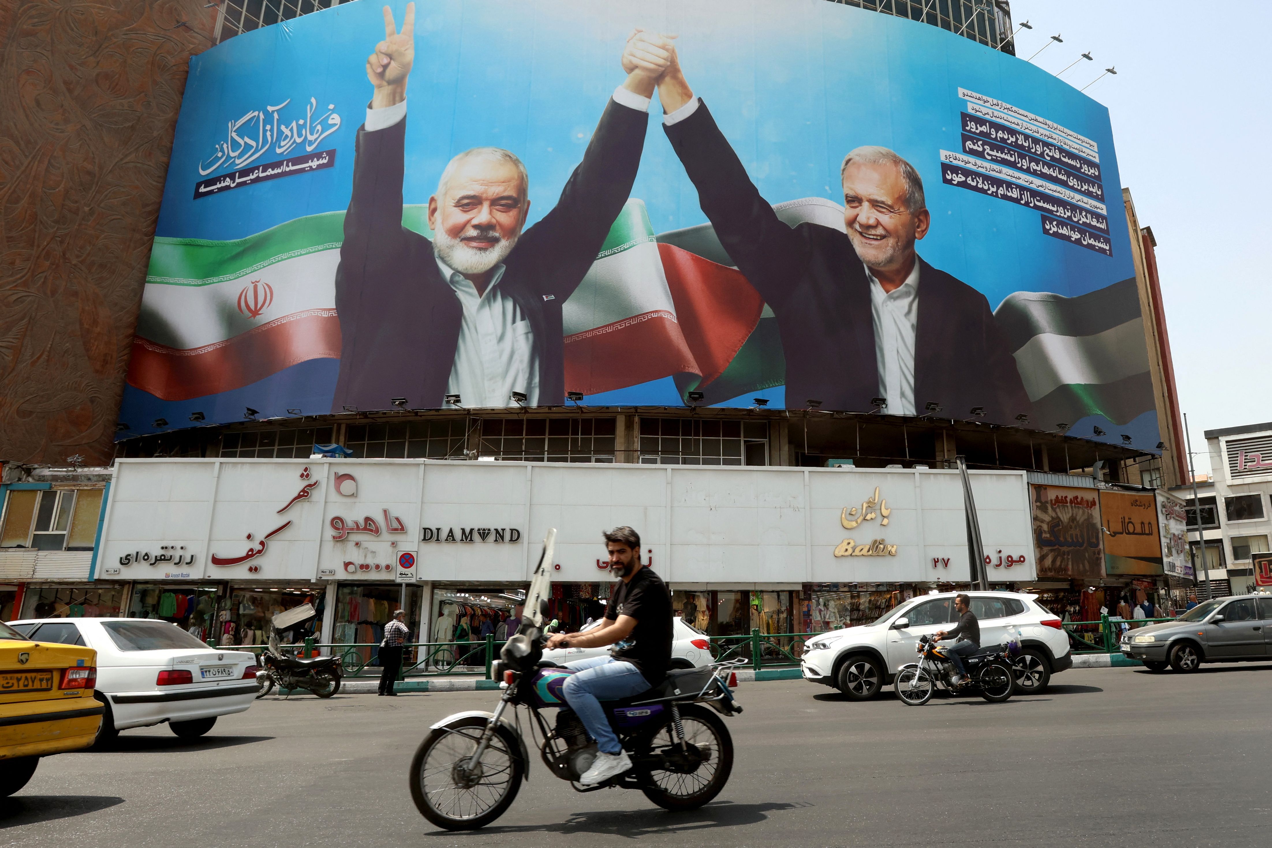 Une affiche géante du président iranien Massoud Pezeshkian et du chef du bureau politique du Hamas Ismaïl Haniyé, tué à Téhéran le 31 juillet 2024, sur la place Valise à Téhéran, le lendemain. Photo AFP