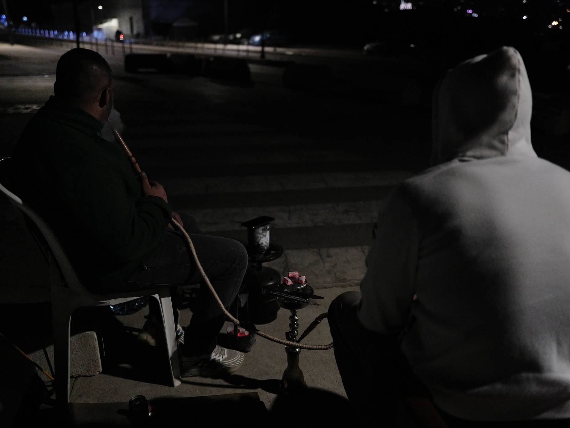 Among the few dozen displaced people sleeping in tents or private sheds set up by certain companies, Ali chats with a neighbor over a hookah. He makes no secret of his anger at “those Lebanese” who refuse to take in the displaced. “The enemy within is worse than the enemy without,” he says. (Credit: Matthieu Karam)