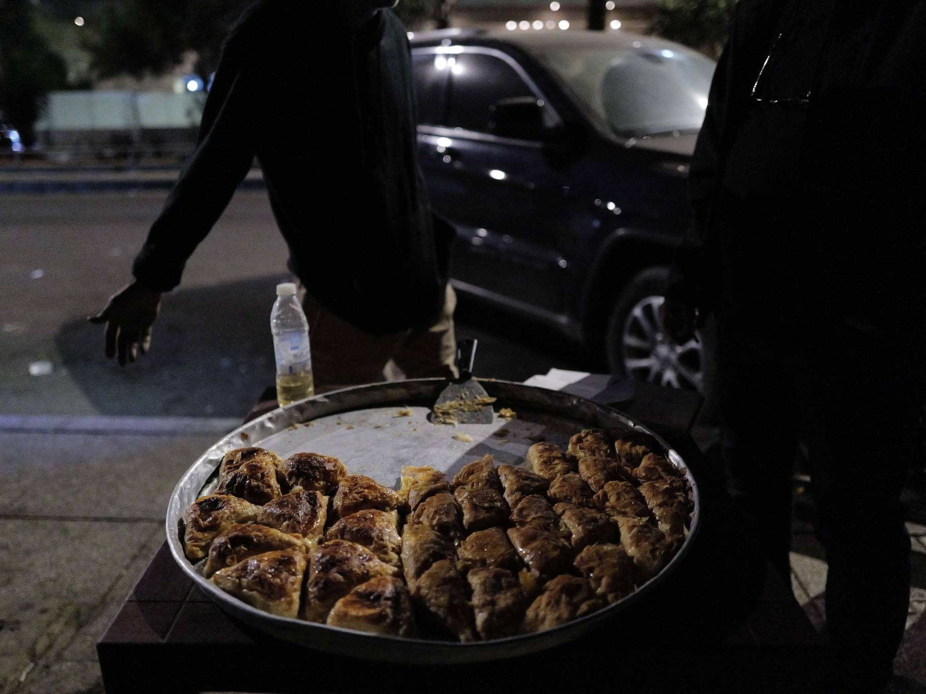 A little further on, Ayden, a Syrian Kurd who has lived in Lebanon since 1991, sells his Arabic pastries on the sly. He could be evicted at any moment. In the meantime, a customer negotiates the price with him. ”50,000 a piece, 100,000 is abuse!” says the customer, Kassem Soleiman, who fled Ghazieh, south of Saida, with his son. “Right now, we're sleeping in our car. We'll close our windows when winter comes,” he quips. (Credit: Matthieu Karam)