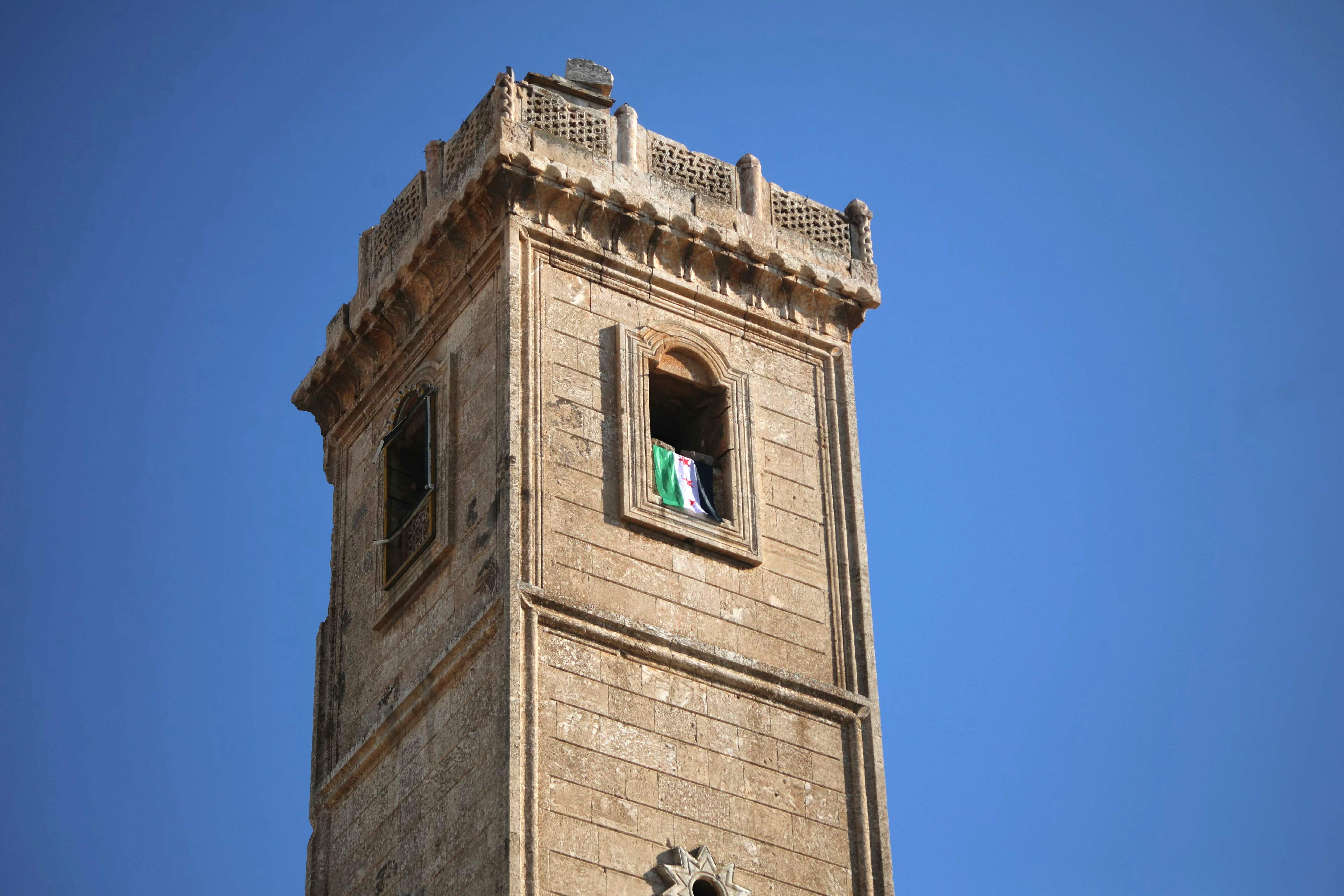 Des combattants anti-régime suspendent le drapeau de l'opposition syrienne dans la grande mosquée de Maaret al-Numan, dans la province d'Idleb, dans le nord-ouest de la Syrie, le 30 novembre 2024. Abdulaziz KETAZ / AFP