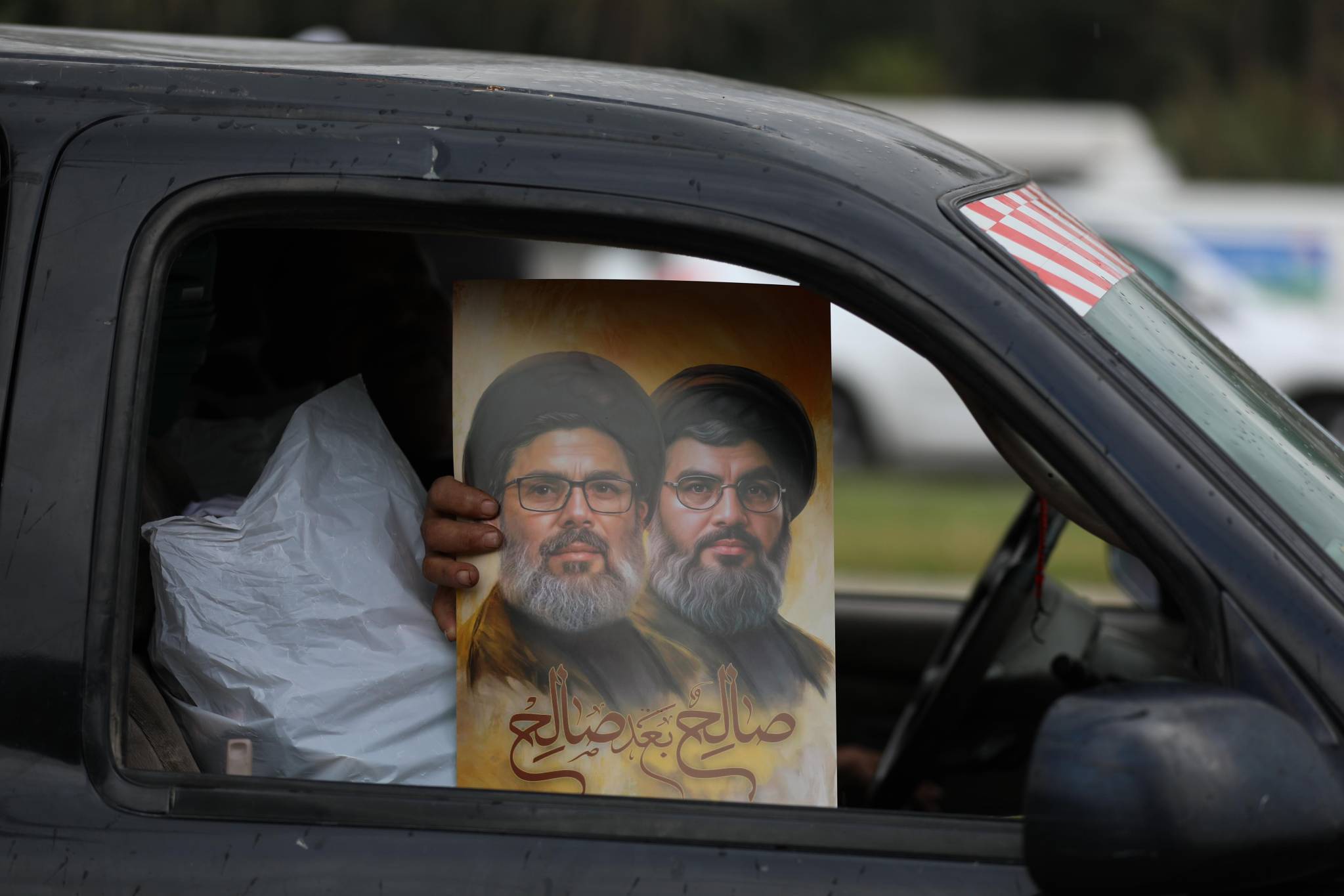 At the entrance to Saida, a boy hands out portraits of Hassan Nasrallah, the Hezbollah leader killed by an Israeli strike on Sept. 27 in the southern suburbs of Beirut. (Credit: Matthieu Karam)