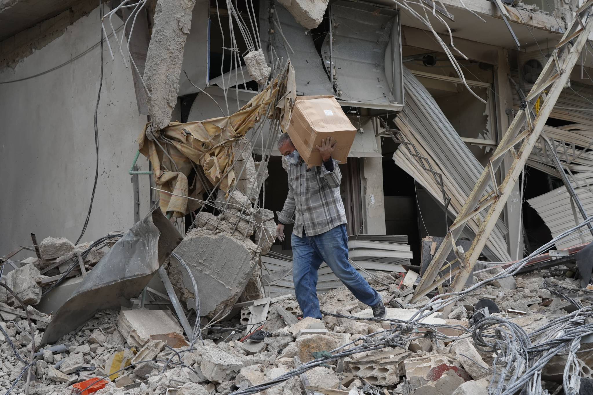 A resident retrieves some belongings from the rubble of what used to be his home. (Credit: Mohammad Yassine/L'Orient-Le Jour)