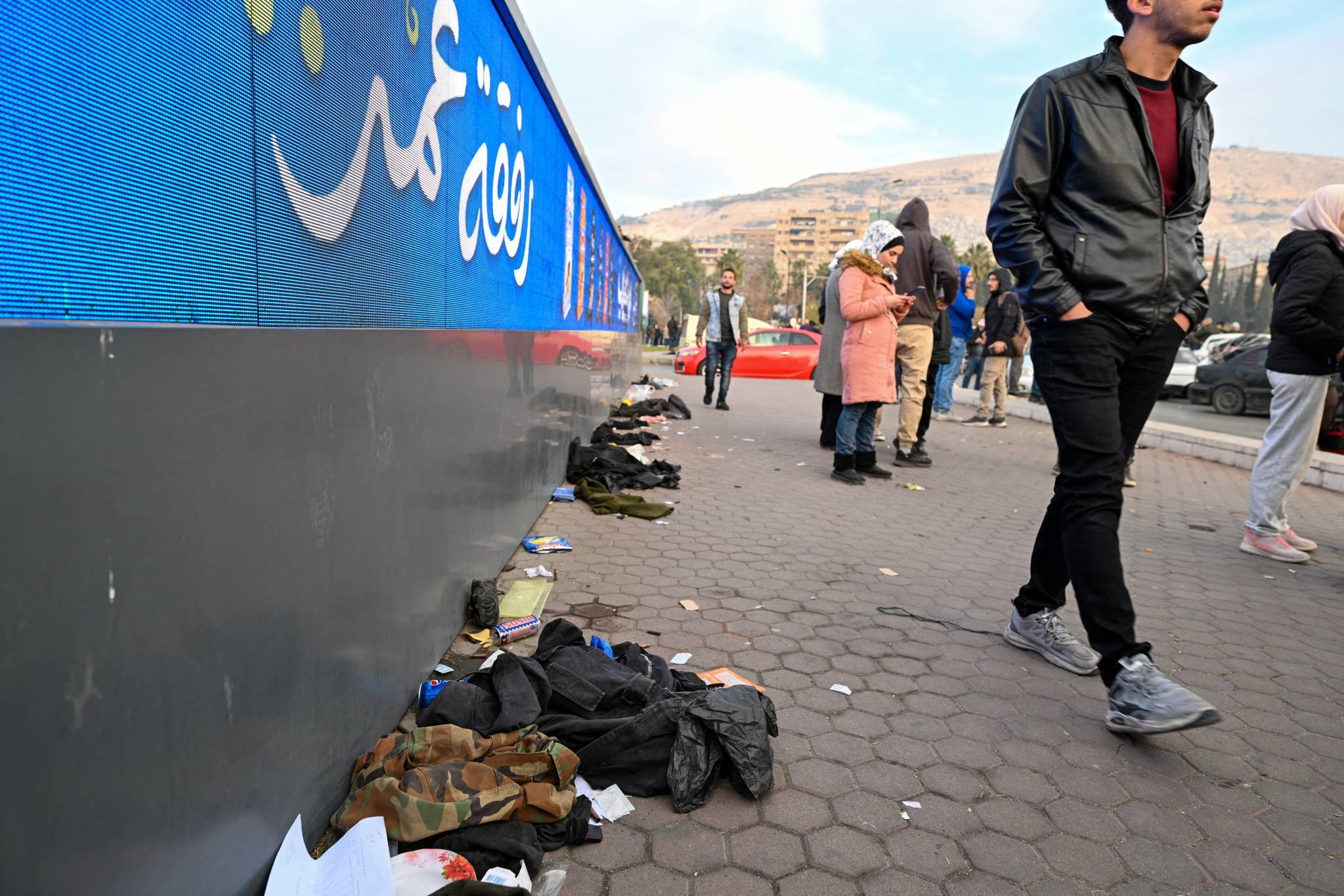 On the sidewalk of a Damascus street, Syrian army uniforms, thrown to the ground. (Credit: Louai Beshara/AFP)