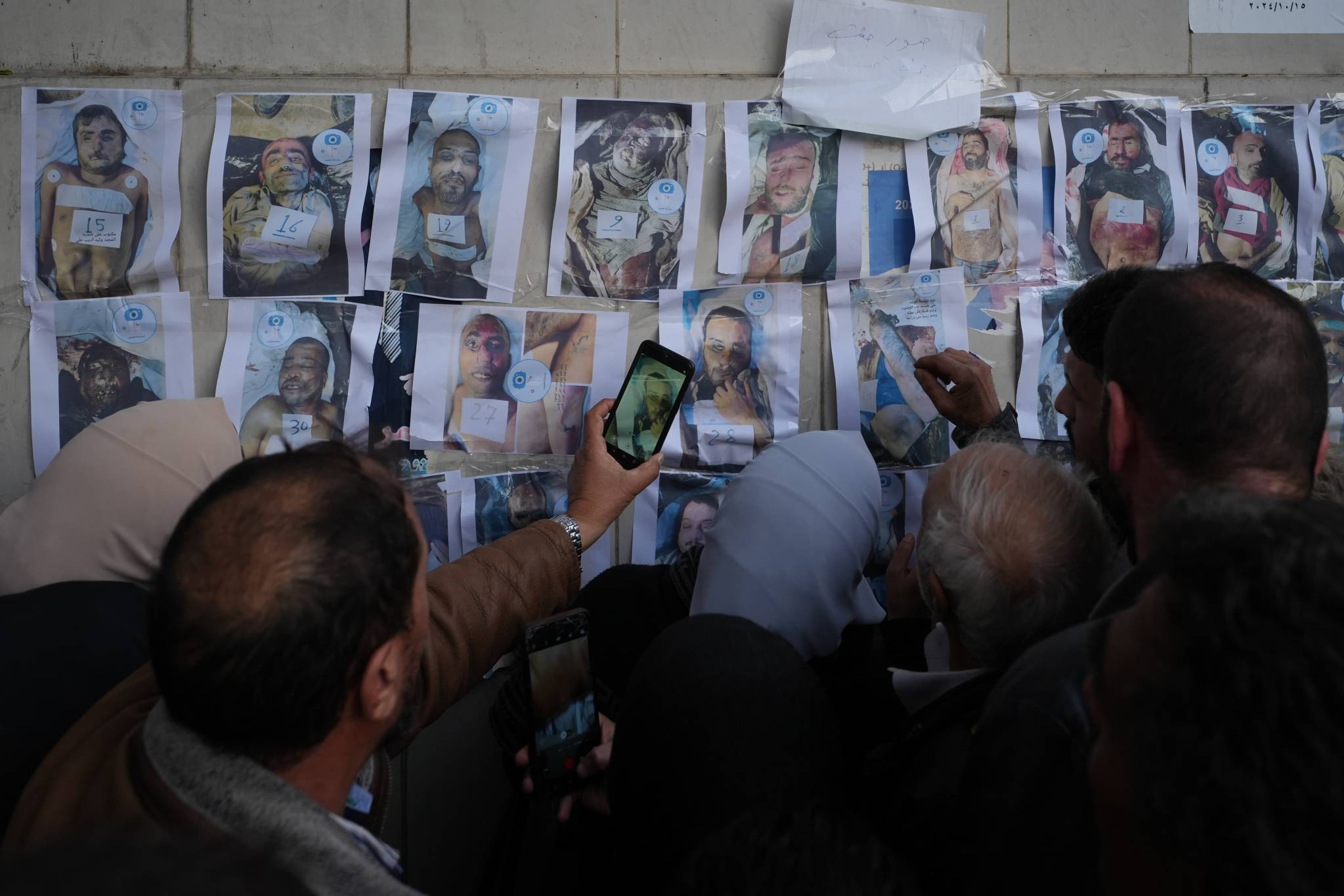 Photos of the recovered bodies are displayed on an exterior wall of the hospital to help families identify the victims. (Photo: Mohammad Yassin)