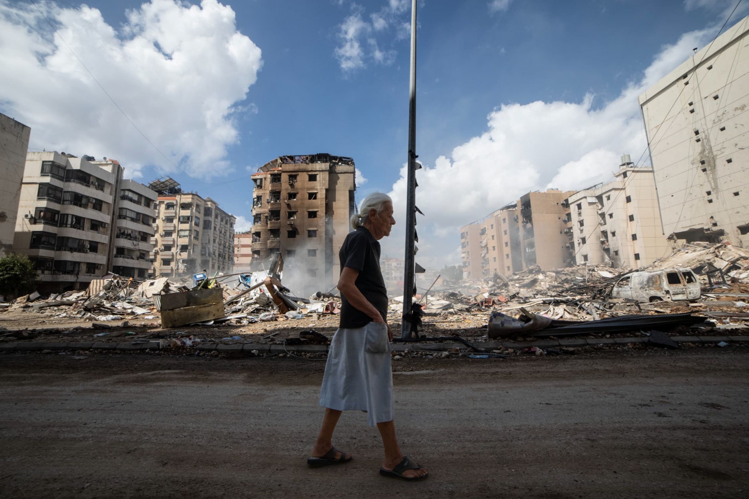 Dans les quartiers de la banlieue sud de Beyrouth qui jouxtent l'aéroport, certains profitent de la moindre accalmie pour inspecter leurs appartements. Ou ce qu'il en reste. Ici, une femme marche devant les décombres, dans le quartier Sainte-Thérèse de Hadath. Photo Mohammad Yassine