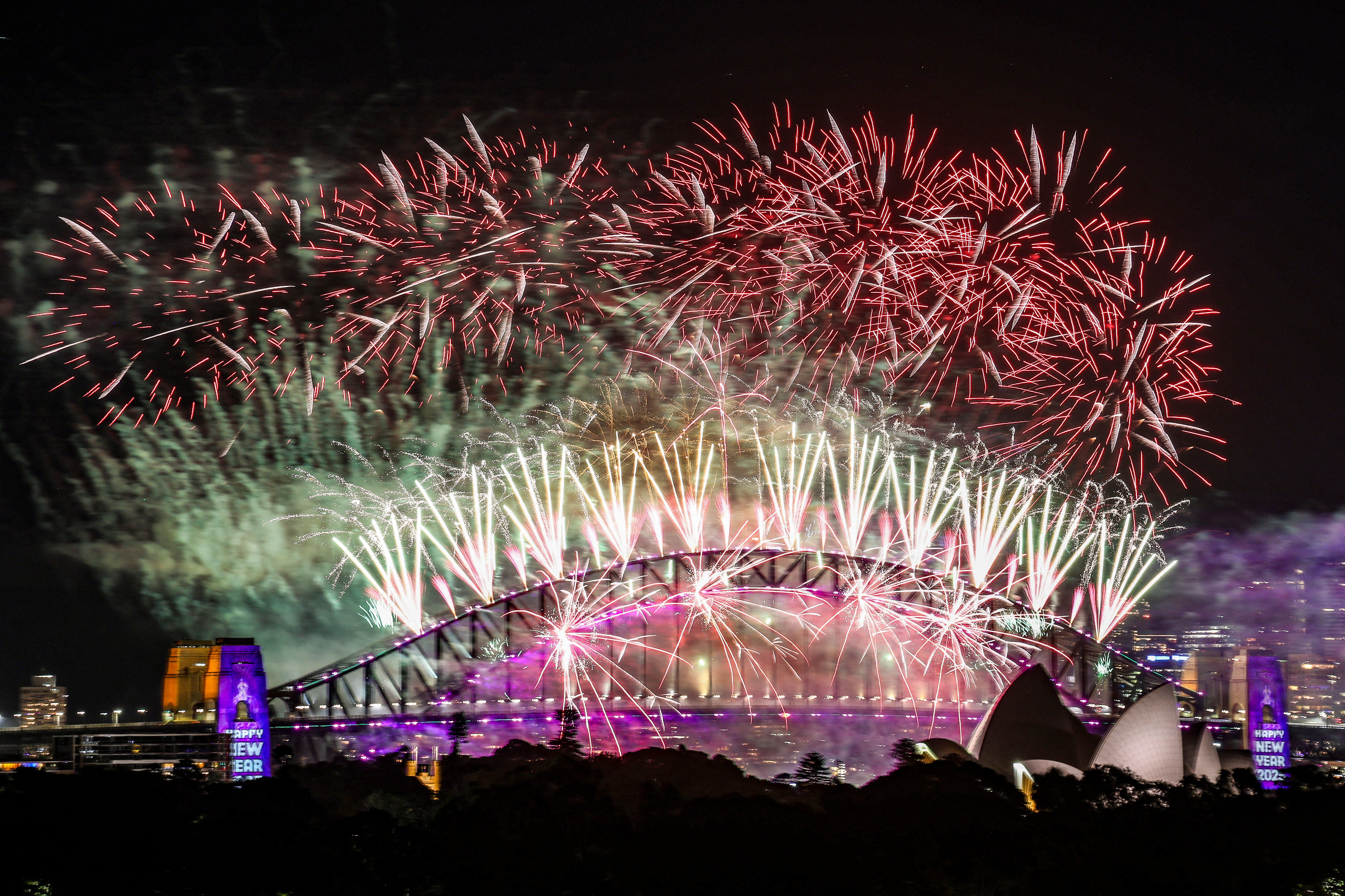 Des feux d'artifice illuminent le ciel de minuit au-dessus du pont Harbour Bridge et de l'opéra de Sydney lors des célébrations du Nouvel An 2025 à Sydney, le 1er janvier 2025. AFP