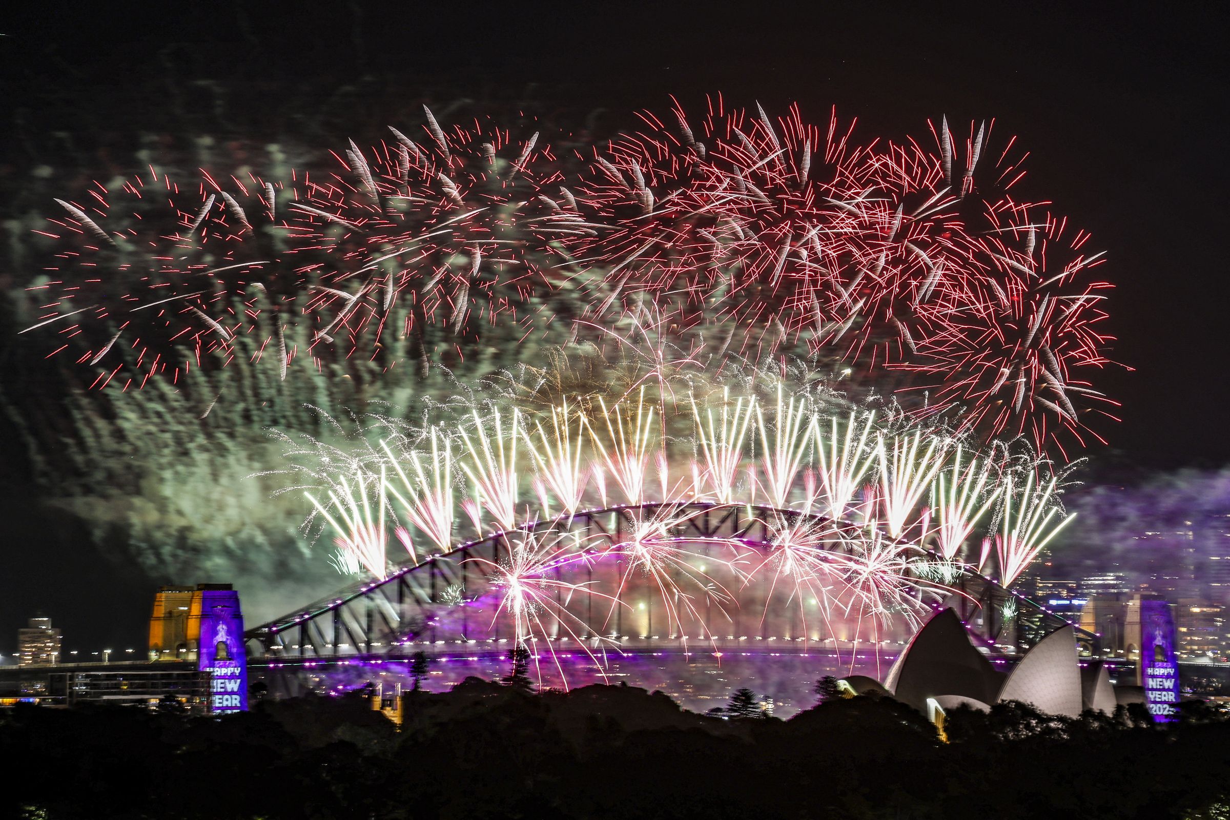 Des feux d'artifice illuminent le ciel de minuit au-dessus du pont Harbour Bridge et de l'opéra de Sydney lors des célébrations du Nouvel An 2025 à Sydney, le 1er janvier 2025. AFP