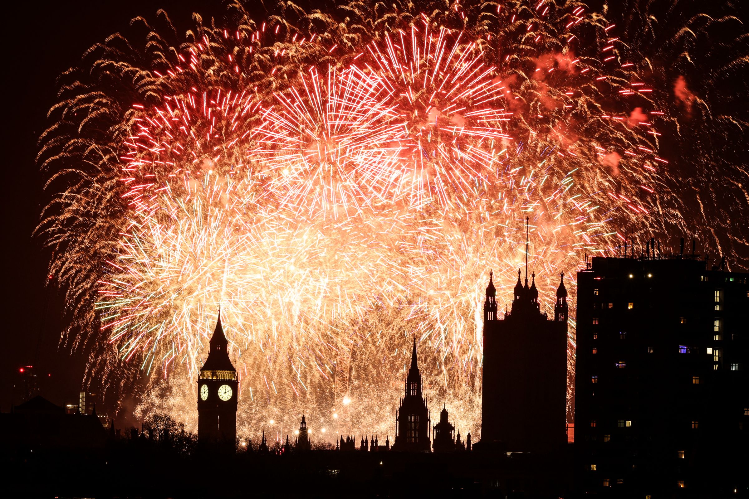 Des feux d'artifice explosent dans le ciel autour du London Eye et de la tour Elizabeth, communément connue sous le nom de la cloche de l'horloge, "Big Ben", au palais de Westminster, qui abrite les Chambres du Parlement, dans le centre de Londres, juste après minuit le 1er janvier 2025. Adrian Dennis / AFP