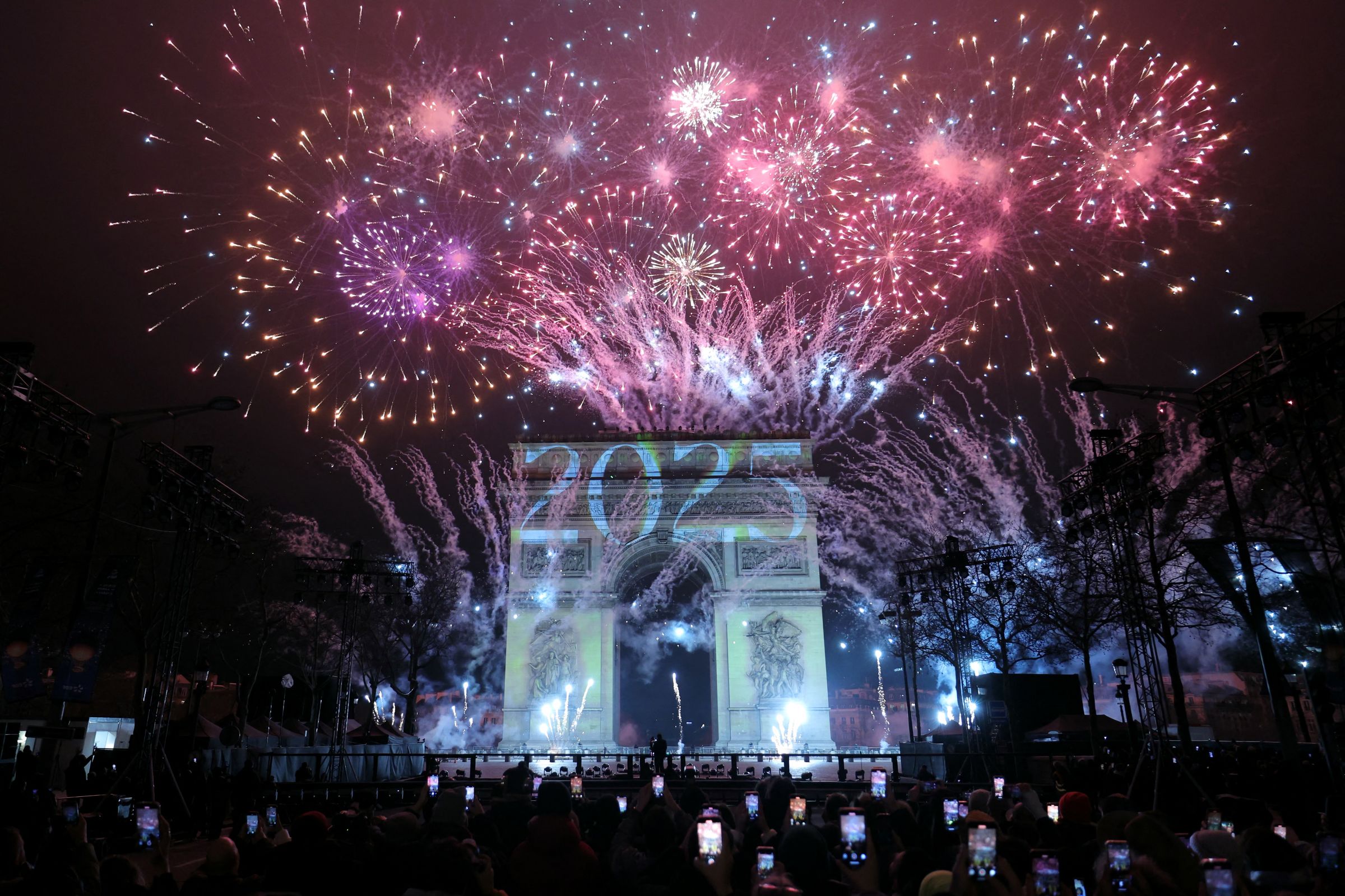 Un feu d'artifice illumine le ciel autour de l'Arc de Triomphe sur l'avenue des Champs-Elysées à Paris le 1er janvier 2025, lors des célébrations du Nouvel An. Thomas SAMSON / AFP