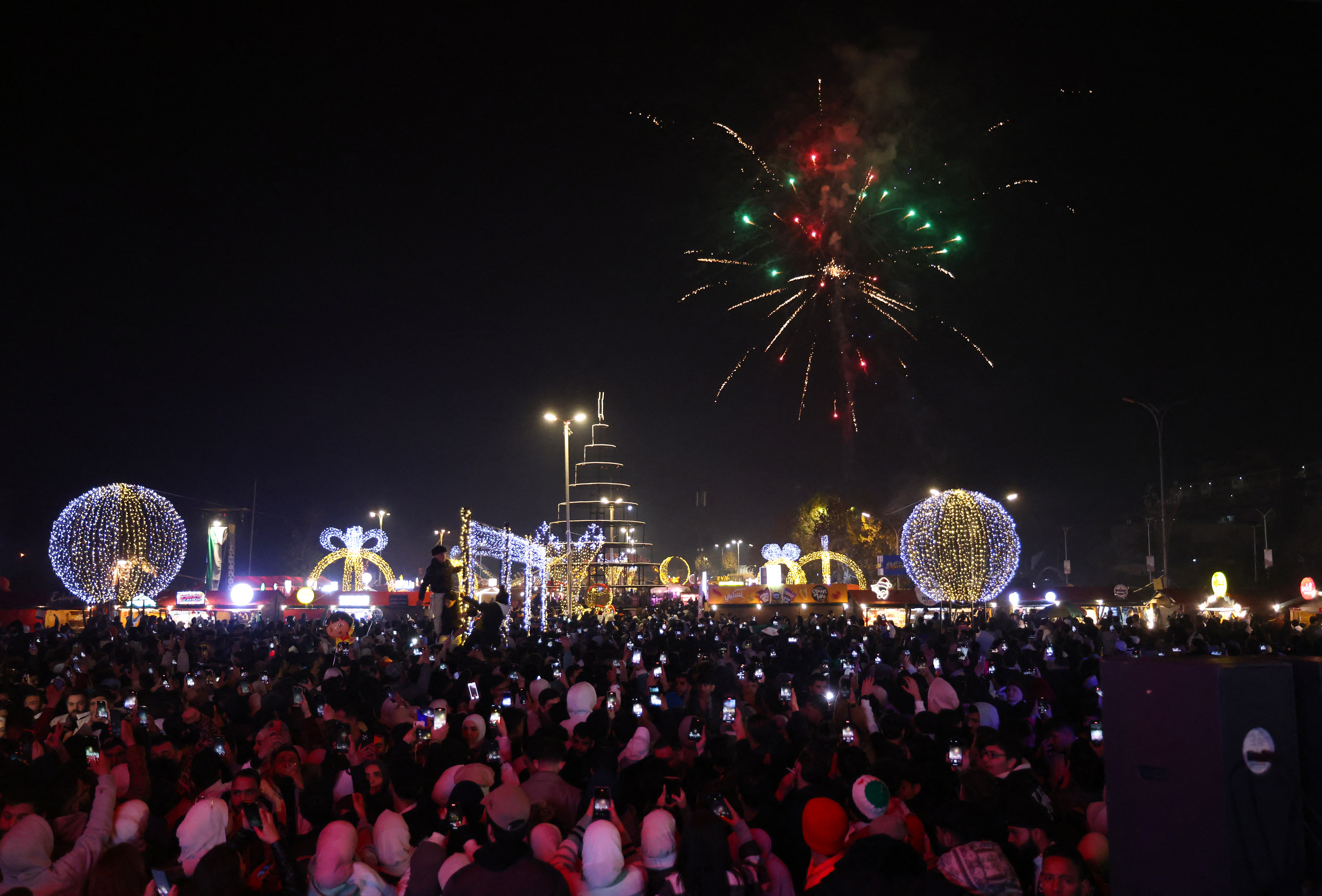 Les gens regardent des feux d'artifice alors qu'ils célèbrent le Nouvel An près de la place des Omeyyades à Damas, en Syrie, le 1er janvier 2025. AFP