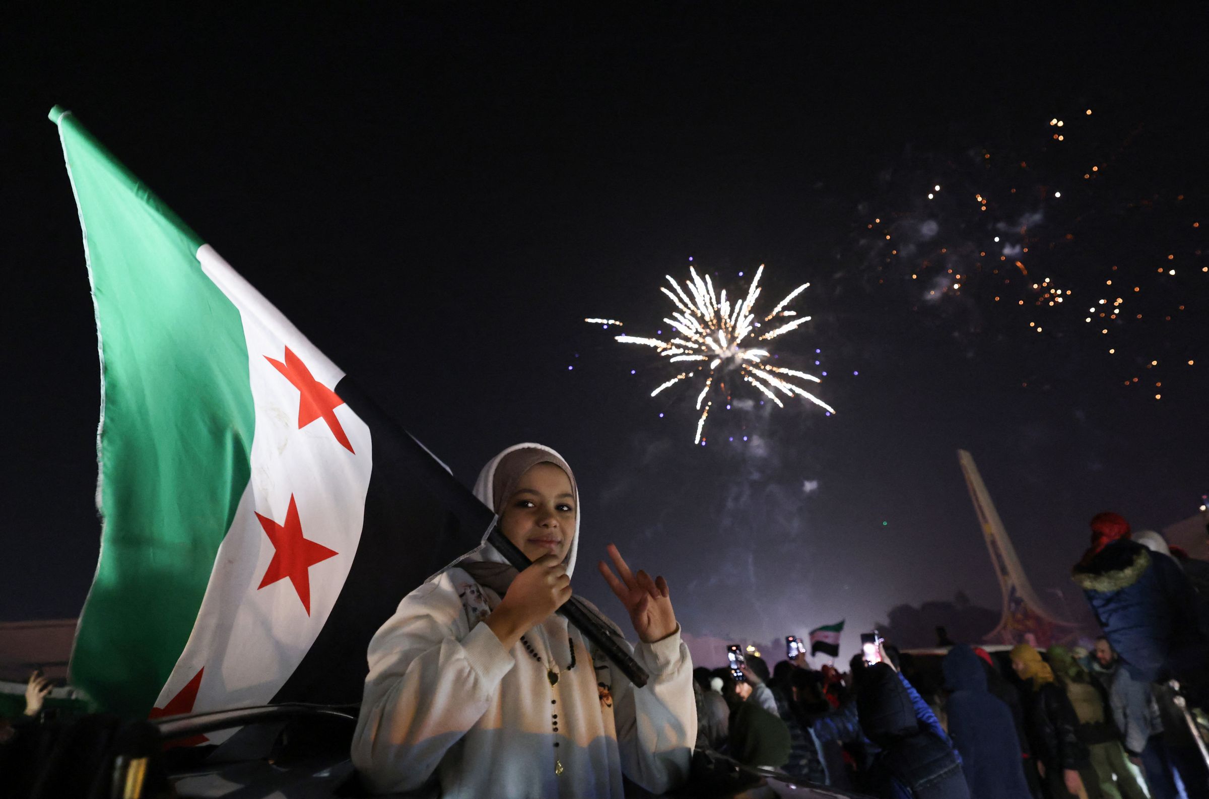 Une jeune femme tient le nouveau drapeau de la Syrie alors que les gens célèbrent le Nouvel An près de la place des Omeyyades à Damas, en Syrie, le 1er janvier 2025. AFP