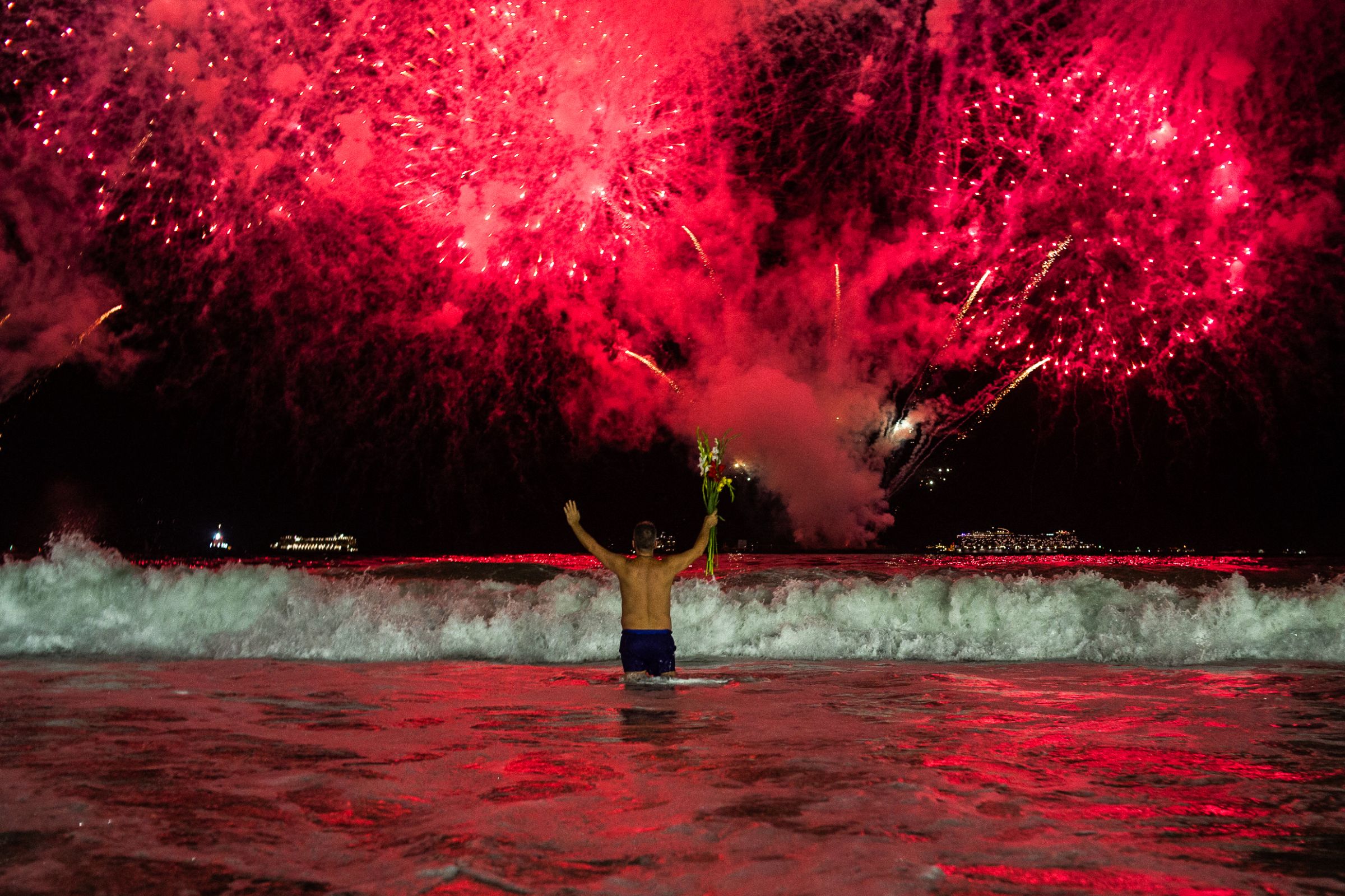 Une personne regarde le traditionnel feu d'artifice du Nouvel An depuis l'eau sur la plage de Copacabana à Rio de Janeiro, au Brésil, tôt le 1er janvier 2025. AFP