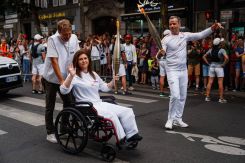 Lebanese photographer Christina Assi (center) assisted by AFP video journalist Dylan Collins (left), after receiving the Olympic flame in Vincennes, near Paris, on July 21, 2024. (Credit: Dimitar Dilkoff/AFP)