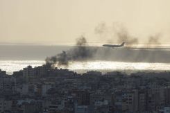 A Middle East Airlines plane flies over the smoke of an Israeli strike on Beirut's southern suburbs. (Credit: Mohammad Yassin/L'Orient Le-Jour)