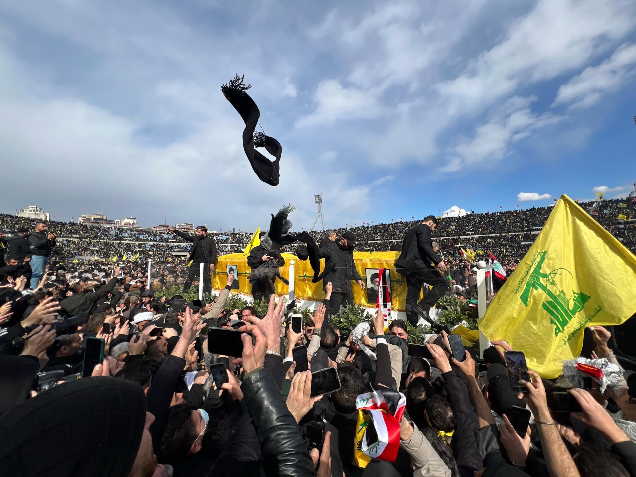 The coffins of Hassan Nasrallah and Hashem Safieddine, perched on the back of a truck, slowly make their way through the crowd. Kuffiyehs, scarves and roses are thrown at the coffins. Hezbollah agents pass them over the coffins as a sign of blessing, before returning them to the crowd. (Credit: Mohammad Yassine/L'Orient-Le Jour)