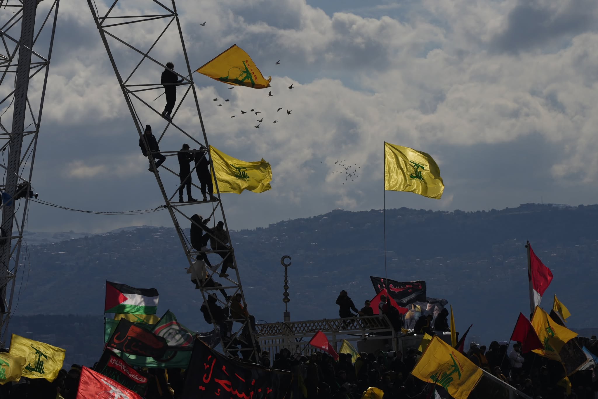 À quelques centaines de mètres de l'AIB, certains escaladent des grues, drapeaux du Hezbollah en main tandis que d'autres étendards chiites, ou encore aux couleurs de la Palestine, flottent au-dessus de la foule. Photo Mohammad Yassine/L'Orient-Le Jour