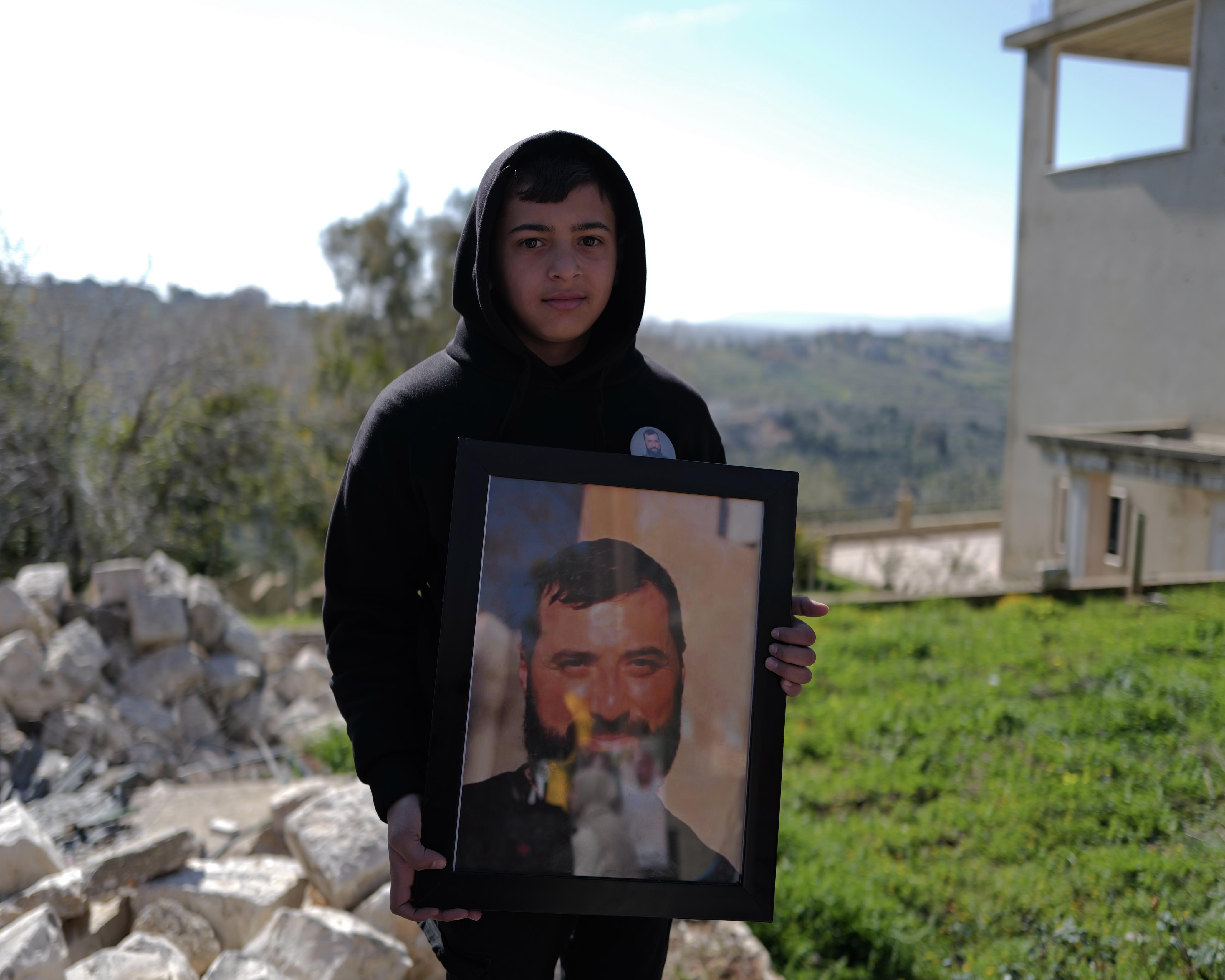 Ali, fils du martyr Ayman Chafic Mahmoud, tient une photo de son père. Photo Matthieu Karam