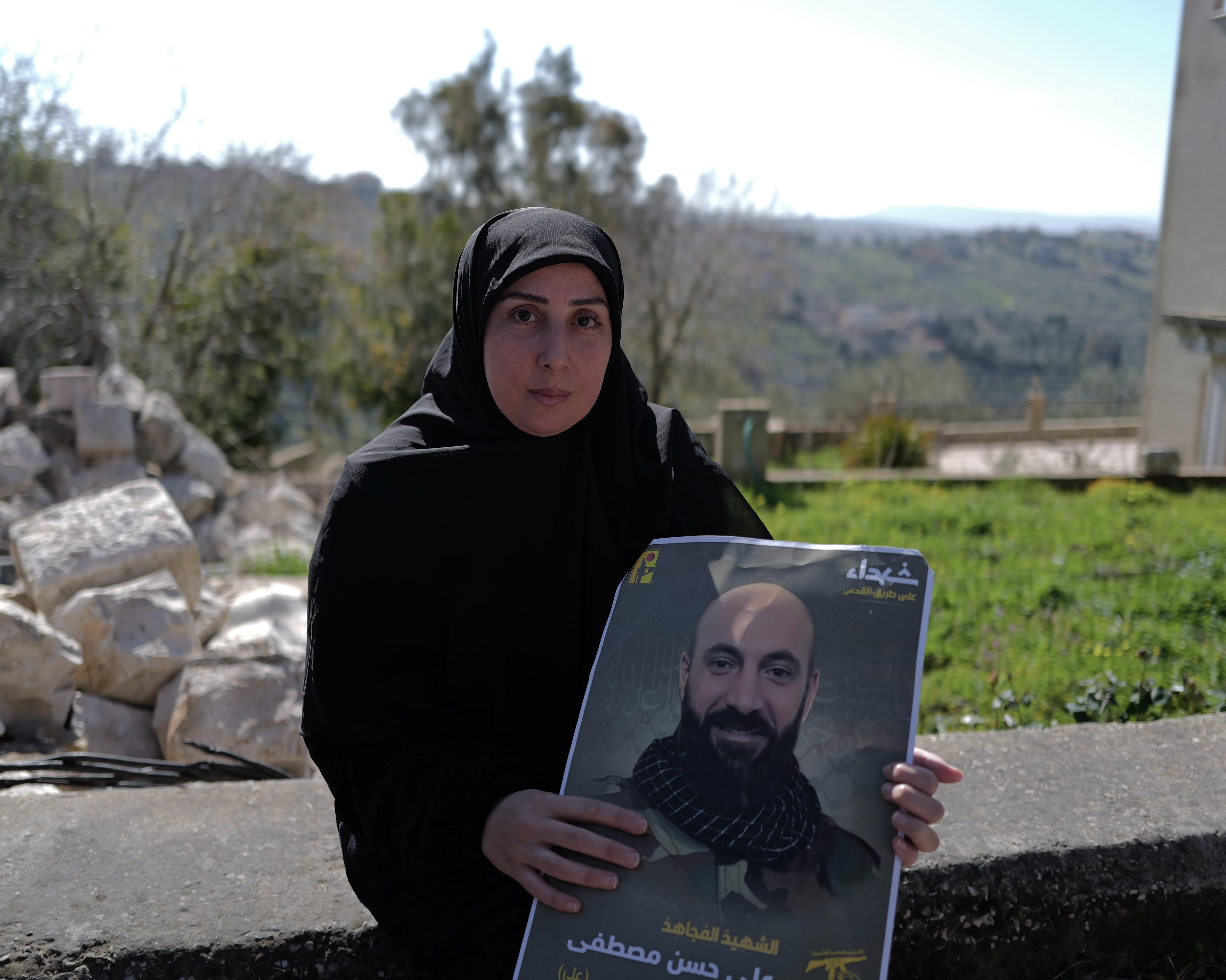 Lama Mustafa, 37 ans, tient une photo de son mari, dont elle est venue chercher la dépouille mortelle à Houla. Elle refuse de prendre le risque de passer à pied par le maquis comme le font certains habitants du village, bravant les instructions de l’armée libanaise. « Le ministre de l'Éducation n'a pas pensé aux familles du Sud en ce jour », dénonce-t-elle en expliquant qu’elle a dû laisser ses trois enfants seuls à l'école car ils passent des examens. Photo Matthieu Karam