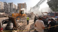 People and members of Civil Defense are gathered in front of the site of the Israeli strike that targeted a building in Hadath, in the southern suburbs of Beirut, on March 28, 2025. (Credit: Mohammad Yassin/L'Orient-Le Jour)