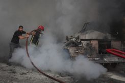 Un pompier de la Défense civile aidé par un citoyen pour éteindre l'incendie. Photo Mohammad Yassine / L'OLJ