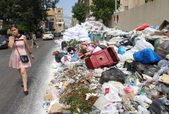A passerby holds her nose while walking past a pile of uncollected garbage in the city of Jdeideh, in the suburbs of Beirut, during the summer of 2015. Archive photo L’OLJ