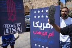 Un panneau "L'Amérique est mère du terrorisme" brandi par un manifestant, avec une chaussure, à Tyr, le 27 août 2025. Photo Mohammad Yassine / L'Orient-Le Jour