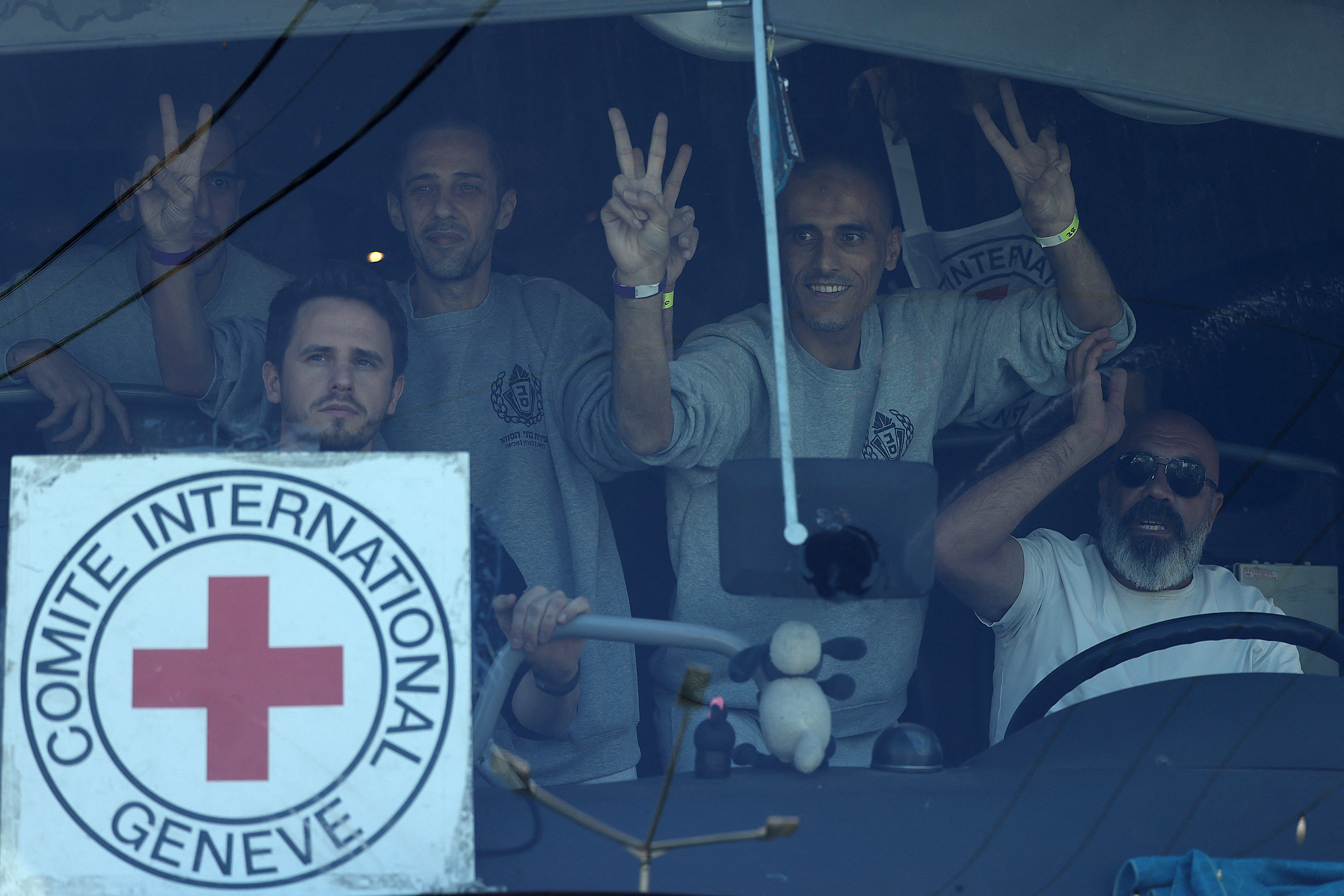 Des prisonniers palestiniens font le signe V - pour victoire - dans le bus qui les ramène chez eux, à Beitunia, le 13 octobre 2025. Hazem Bader / AFP