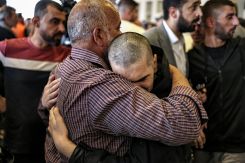 A Palestinian prisoner, freed from Ofer military prison as part of the Gaza cease-fire deal between Israel and Hamas, is embraced by his father upon arrival by bus at the Ramallah Cultural Centre in the occupied West Bank. (Credit: Zain Jaafar/AFP)