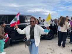 Une travailleuse domestique malgache aux portes du site de la messe du pape, au cœur de Beyrouth, arbore les drapeaux du Liban et du Vatican. Derrière elle, une amie et compatriote. Photo Anne-Marie el-Hage/L'Orient-Le Jour