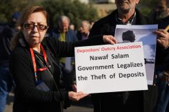 Une manifestante brandissant une pancarte lors d'une protestation contre le projet de loi sur la restitution des dépôts, le 22 décembre 2025. Photo Mohammad Yassine/L'Orient-Le Jour