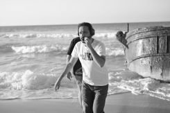 Peter Mimi sur le tournage de "Shab al-Ard", debout au bord d’une plage, préparant une scène entre ciel ouvert et ligne d’horizon. Photo fournie par Peter Mimi