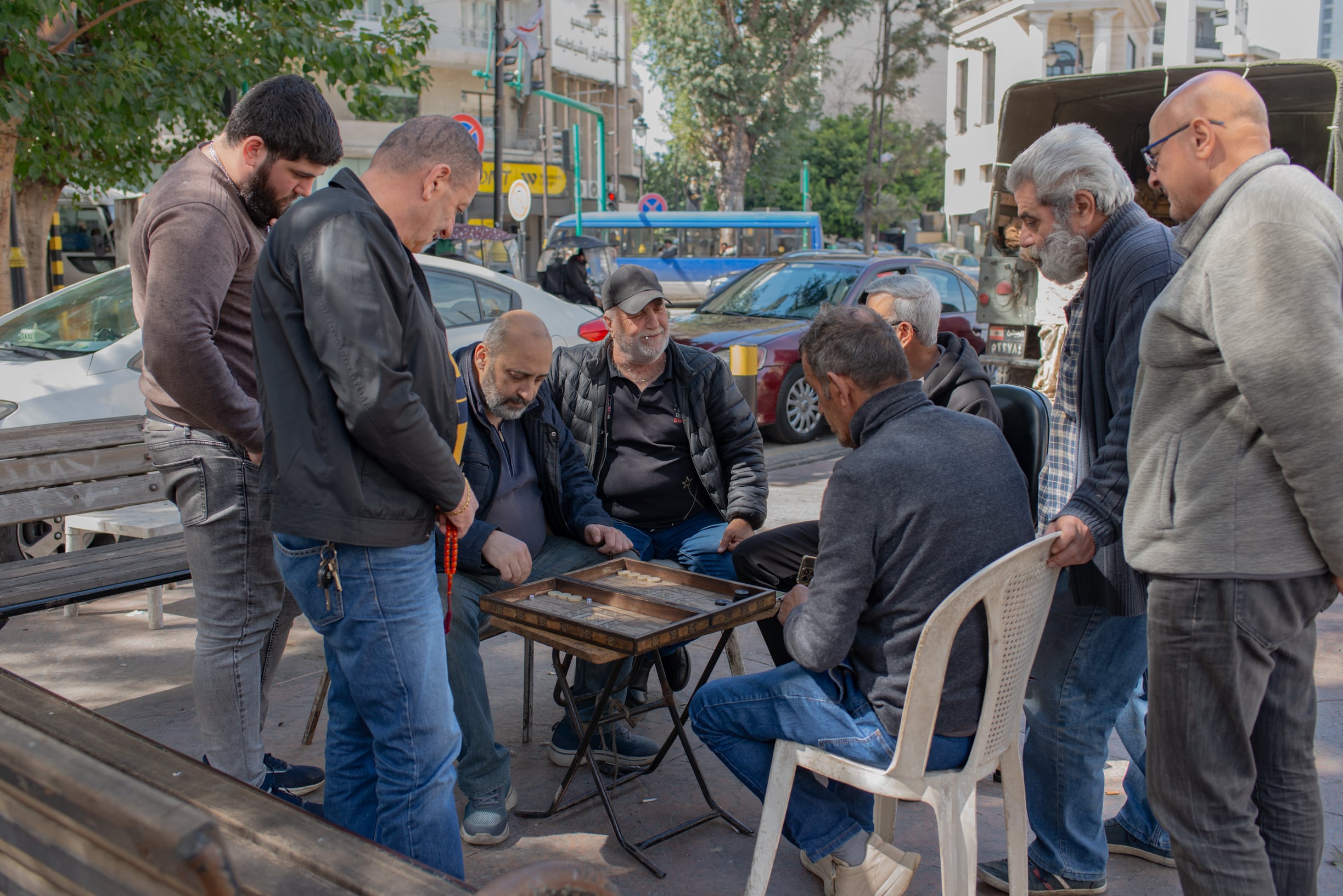 Men play backgammon in Sassine Square, just a few steps from a group of soldiers, on March 28, 2026. (Credit: Ségolène Ragu/L’Orient Today)