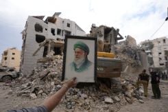 Un homme brandit un portrait de l’ancien guide suprême iranien Ali Khamenei le 10 avril 2026, devant des décombres d’habitants dans la banlieue sud de Beyrouth. Photo Mohammad Yassine/L'Orient-Le Jour