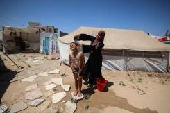 Une mère lave son fils avec les moyens du bord dans un camp de déplacés à Nousseirat, dans le centre de la bande de Gaza, le 28 juin 2026. Photo Eyad Baba/AFP