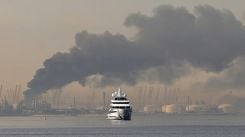 A yacht passes in front of a plume of smoke rising from the port of Jebel Ali following a suspected Iranian strike in Dubai, March 1, 2026. (Credit: AFP)