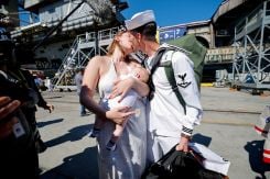 Alexander Adkins, un marin, embrasse son épouse McKenzie Adkins alors qu'elle tient Declan, leur bébé de 10 semaines, après le retour à la base navale de Coronado (San Diego, Californie, États-Unis) du porte-avions de classe Nimitz de l'US Navy, l'USS Abraham Lincoln, à l'issue d'un déploiement prolongé au Moyen-Orient, le 8 octobre 2026. Photo Mike Blake / REUTERS