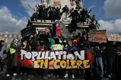Protesters hold a banner reading "Angry population" on the statue of the Place de la Republique during a demonstration against the cost of living and rising fuel prices in Paris as part of nationwide protests by students, teachers, and parents demanding better school conditions and government action, as well as labor unions, workers, farmers, and retirees, on Oct. 17, 2026. (Credit: Stephanie Lecocq/Reuters)