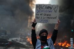 A protester holds a placard reading "Macron must resign, we will not yield to pressure" amid clashes during a day of demonstrations against the cost of living and rising fuel prices in Paris as part of nationwide protests on Oct. 17, 2026. (Credit: Stephanie Lecocq/Reuters)